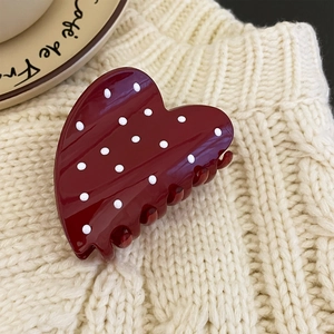 Detail of red heart hair claw with white polka dots on cozy knit background