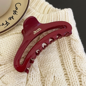 Elegant wine red hair claw clip with golden French lettering on knit background