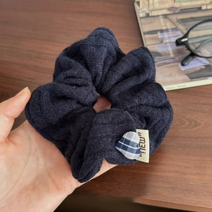 Détail d'un chouchou en maille marine avec breloque cœur à carreaux sur bois