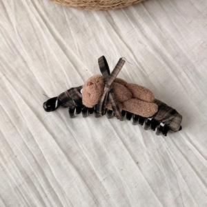 Detail of cute plush teddy bear hair clip featuring brown checkered ribbon on banana clip