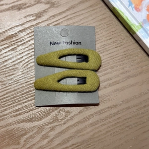 Detailed macro view of olive green knitted fabric covering on two teardrop hair clips
