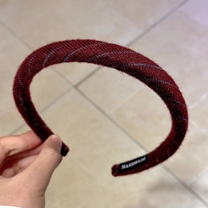 Close-up of burgundy twill headband with silver sparkle thread and handmade label
