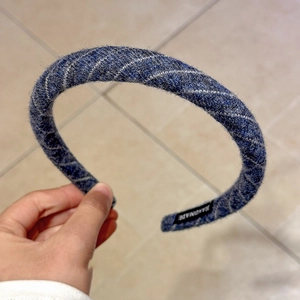 Detailed close-up of dark blue and grey tweed headband with handmade label