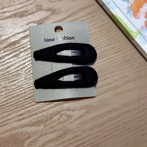 Detail of two black fabric teardrop hair clips on a premium New Fashion display card