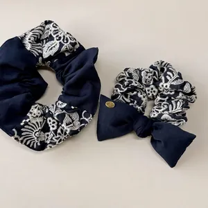 Ensemble chouchou bleu marine brodé de fleurs blanches avec nœud et logo en métal doré