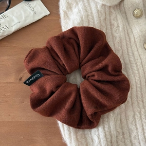 Détail d'un chouchou en tricot marron foncé avec texture douce sur fond de bois