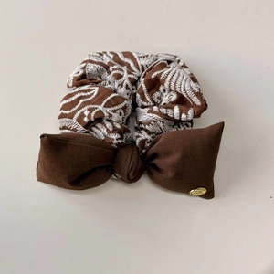 Détail d'un chouchou marron foncé avec broderie blanche et grand nœud en soie élégant