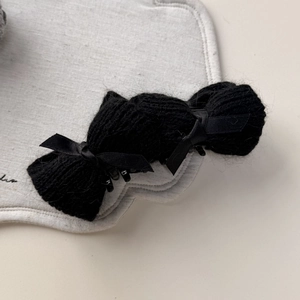 Detailed close-up of a black knitted bow hair clip with elegant ribbon details
