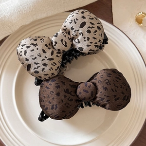 Leopard print bow banana clips in khaki and brown displayed on a ceramic plate
