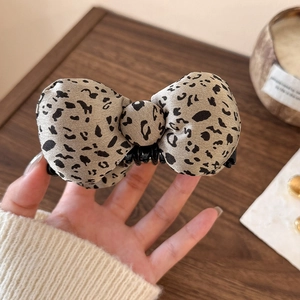 Close-up of leopard print bow hair clip showing textured fabric and banana clip detail