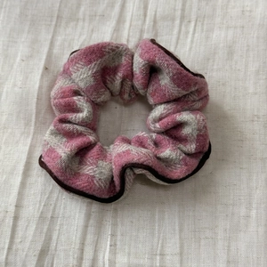 Détail d'un chouchou en tweed à carreaux rose et gris avec passepoil marron contrasté