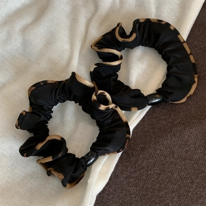 Détail de deux chouchous à bordure léopard avec des perles décoratives noires