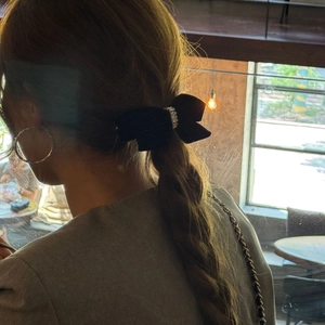 Elegante zwarte fluwelen strik haarclip met strass steentjes gedragen in een paardenstaart