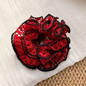 Close-up detail of double-layered lace scrunchie with intricate red and black floral embroidery