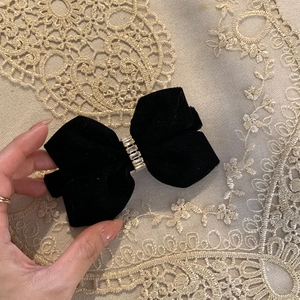 Detail van een fluwelen strik haarclip met glanzende strassteentjes op kant