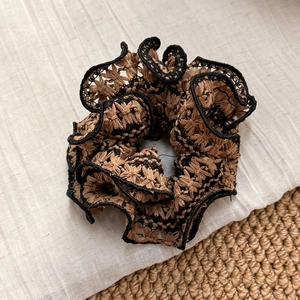 Detailed macro view of layered crochet lace scrunchie with intricate brown and black mesh
