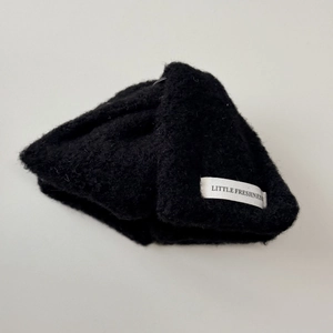 Détail d'une pince à cheveux en laine tricotée noire avec étiquette Little Freshness