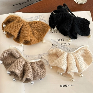Barrettes en tricot avec perles factices en quatre couleurs neutres sur livres