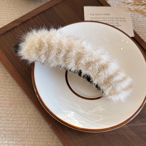Barrette banane en fausse fourrure beige léopard sur une assiette en céramique