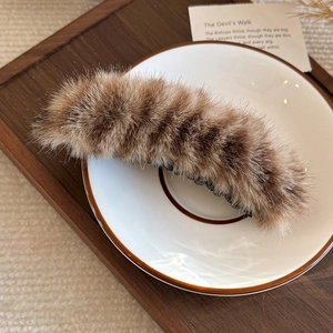 Détail de la pince banane en peluche léopard avec texture douce en fourrure sur plat blanc