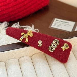 Detailed close-up of a red velvet horse hair clip with golden charms for Lunar New Year