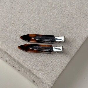Detail of tortoise shell hair clips with silver metal base on a linen book surface