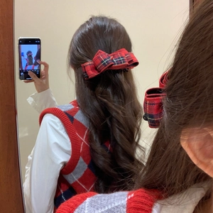 Detail of a red plaid bow banana clip styled on long wavy hair in a cozy setting