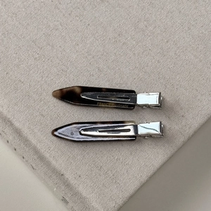 Detail of tortoiseshell acetate hair clips with metal base on beige fabric texture