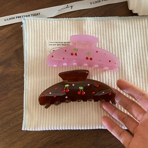 Detail of pink and brown acetic acid hair claws with cherry rhinestone patterns