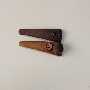 Detail of fabric hair clips with Always gold metal lettering and decorative wood button