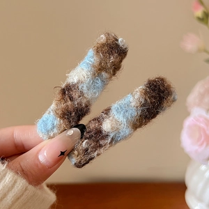 Détail d'une paire de barrettes à cheveux en peluche à carreaux bleus et marrons