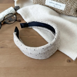Close-up of beige knitted polka dot headband with non-slip lining on wooden table