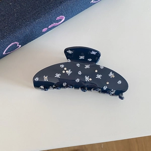 Detail of navy blue floral acetate hair claw clip with rhinestones on white background