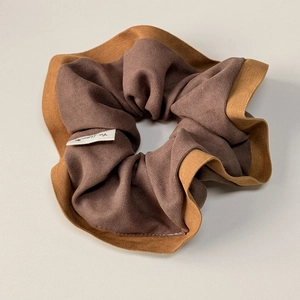 Close-up of knit fabric scrunchie with coffee and camel color tones and woven label