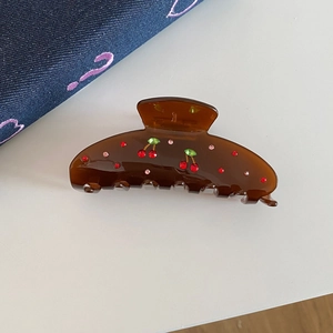 Close-up of tortoise shell hair claw clip with red rhinestone cherry pattern detail