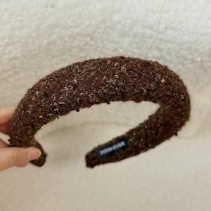 Macro shot of brown velvet sponge headband with golden threads and handmade label
