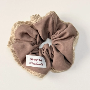 Detail of a handmade brown scrunchie with beige crochet edges and woven brand label