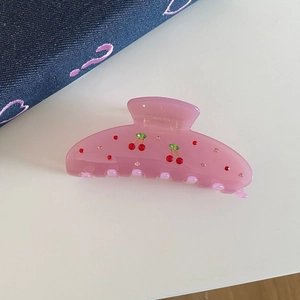 Macro view of pink acetate hair claw clip featuring cherry patterns and small rhinestones