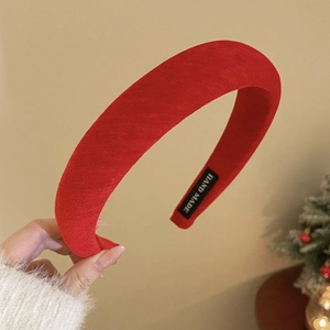 Detail of red plush velvet padded headband showing handmade label and texture