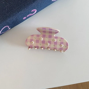 Detail of lavender checkered acetate claw clip featuring 3D white flowers and small rhinestones