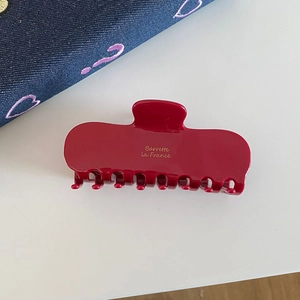 Detail shot of a red acetate hair claw with Barrette la France golden script engraving