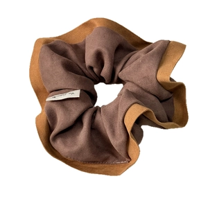 Brown and mocha two-tone knitted scrunchie with brand tag on clean white background