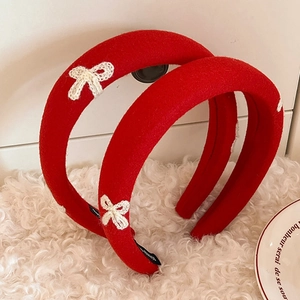 Red padded headband with white crochet bow accessory on a plush white background