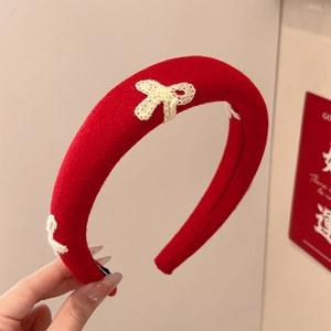 Detail of a red sponge headband with white crocheted bow featuring textured fabric