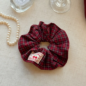 Detailansicht eines rot-blau karierten Scrunchies mit Sweet Cherry Stoffetikett