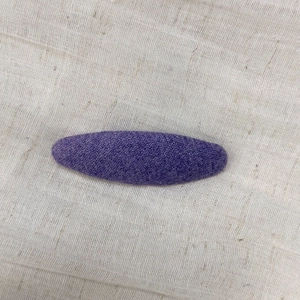 Detail shot of purple knitted fabric hair clip showing delicate twill texture and finish