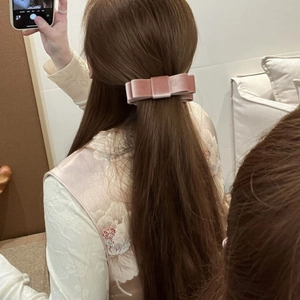 Pink velvet bow banana clip shown on woman's hair in an elegant half-up style