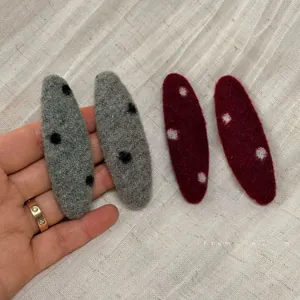 Detailed texture of red and grey polka dot felt hair clips for women's autumn style