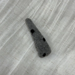 Detailed view of handmade grey felt hair clip featuring three minimalist black polka dots