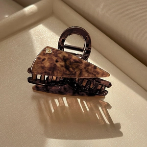 Detail showing acetate leopard triangle hair claw clip with golden B letter